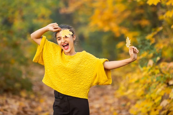 笑顔の女の子は秋に森の中で黄色いカエデの葉で遊ぶ — ストック写真