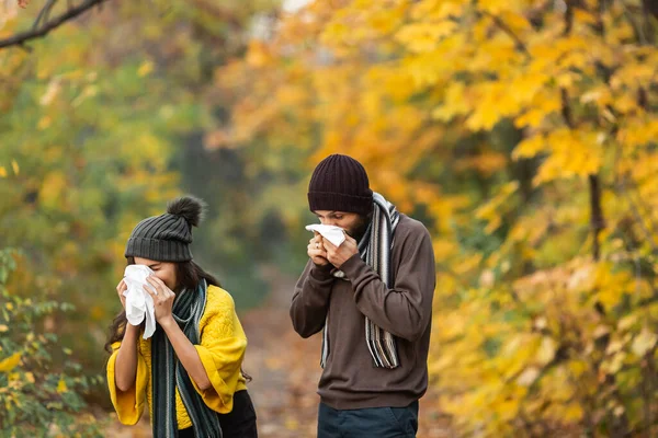 sick man and girl sneeze and blow their nose in autumn in the park.