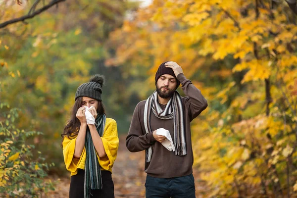 sick man and girl sneeze and blow their nose in autumn in the park.