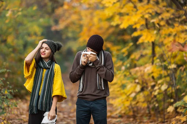 sick man and girl sneeze and blow their nose in autumn in the park.