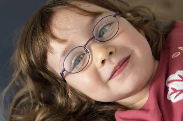 Egy hároméves kék szemű szőke lány portréja szemüveggel. — Stock Fotó