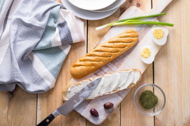 Taze pişmiş ekmek ekmeği. İkiye bölünmüş ve basit bir peynirli, yumurtalı ve otlu sandviç olarak hazırlanmış.