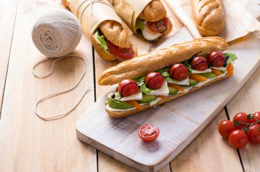 Tahta arka planda çeşitli dolguları olan taze denizaltı sandviçleri.