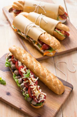 Tahta arka planda çeşitli dolguları olan taze denizaltı sandviçleri.