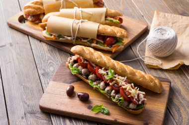 Tahta arka planda çeşitli dolguları olan taze denizaltı sandviçleri.