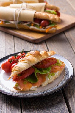 Tahta arka planda çeşitli dolguları olan taze denizaltı sandviçleri.