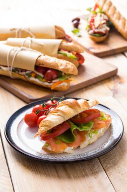 Tahta arka planda çeşitli dolguları olan taze denizaltı sandviçleri.