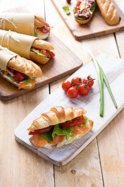 Tahta arka planda çeşitli dolguları olan taze denizaltı sandviçleri.