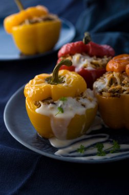 Koyu mavi arka planda kıyma ve pirinçle doldurulmuş renkli çan biberleri.