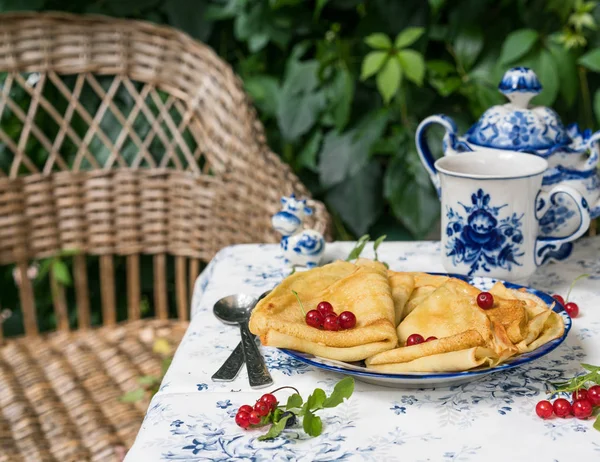 Kahvaltı krep, mavi ve beyaz renkli porselen, vintage şeker pot ve küçük heykel inek, kaşık, Bahçe, doğanın duvarına tabloda yapraklar ve arka plan üzerinde dokuma sandalye