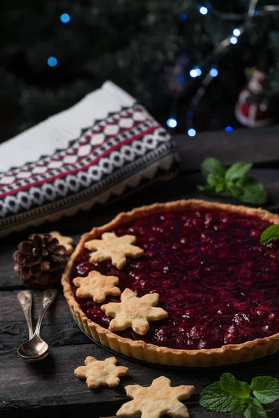 christmas tart, cherry tart on a dark wooden backdrop in rustic style, decorated with snowflakes biscuits, dark style