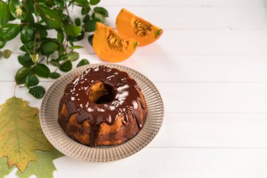 Ev yapımı çikolata ve kabak pasta, çikolata sır üstte, rustik plaka, Beyaz ahşap zemin ile dekore edilmiş, yapraklar ve kabak dilimleri