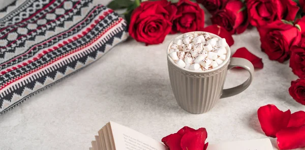 hot chocolate drink topped with marshmallow in a grey cup on a grey marble, red roses decoration, festive styling