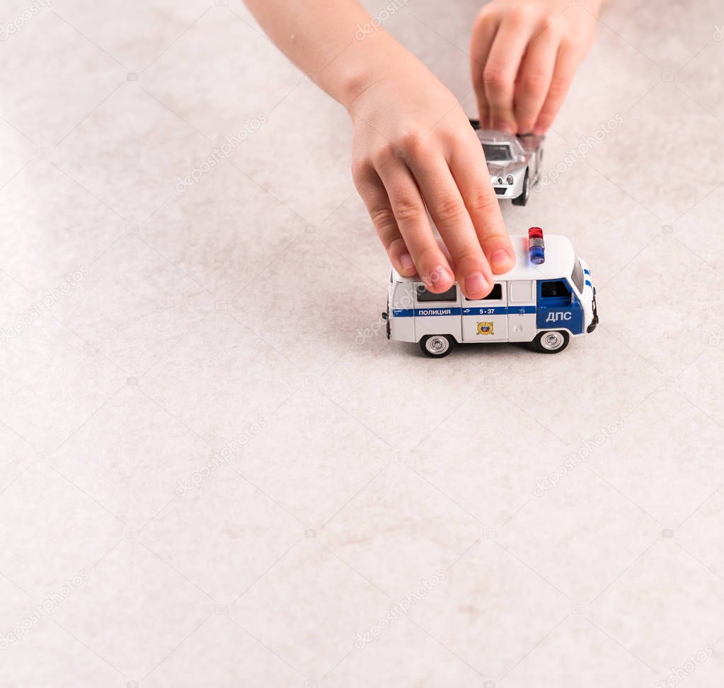 a game, playing with cars, racing car and a police car in the hands of a child