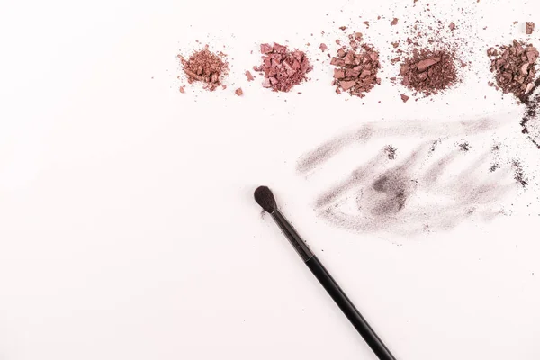 eye shadows in a line on a light paper backdrop, make up brush, eye drawn with these eye shadows