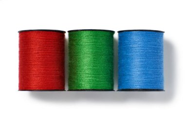 Beyaz arkaplanda izole edilmiş kırmızı, yeşil ve mavi pamuk makaralarının genel görünümü