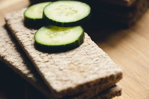 Taze dilimlenmiş ve yeşil salatalık parçaları ile çavdar ve buğday unu yapılan ekmek, gıda kesmek için bir tahta üzerinde yalan. Sebzeli lezzetli sandviçler yapmak için hazırlanmıştır. Sağlıklı, kolay ve sağlıklı gıdalar.