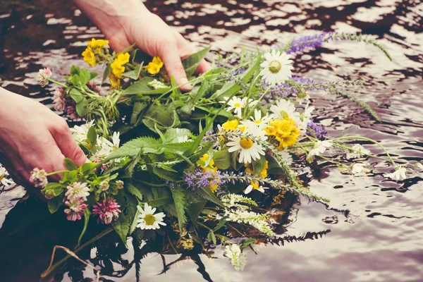 Güzel çiçekler bir nehir su üzerinde koca bir çelengi tutan bir kız.