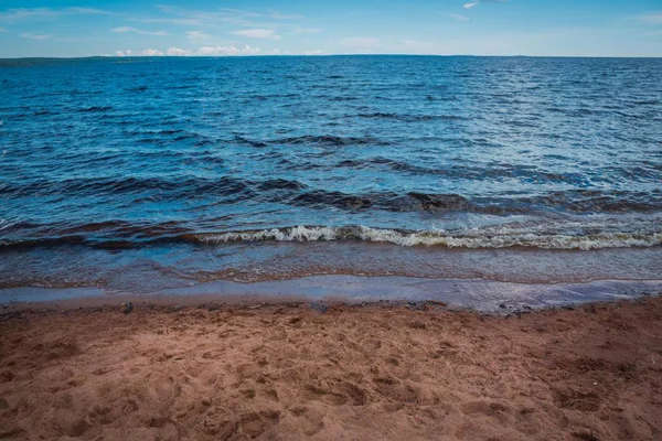 Göl, gökyüzü ve bulutlar kumlu kıyıdan görünümünü.