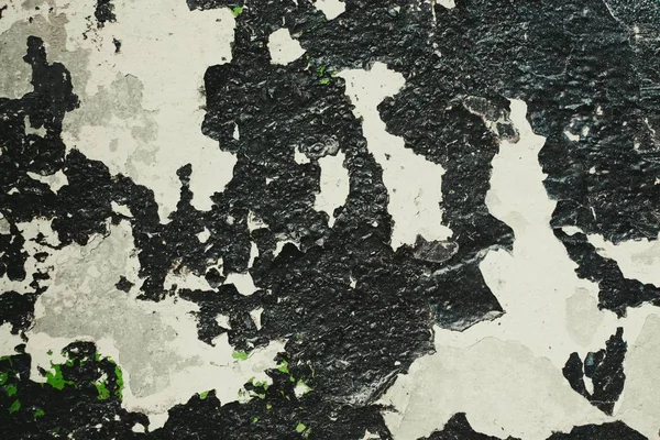 Texture of a black shade of cracked paint on a concrete wall