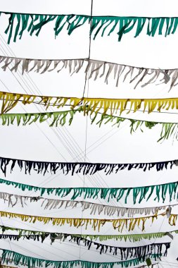 Küçük çok renkli bayraklar iplik ve gökyüzünün bulutlu arka plan asmak bağlıdırlar. Onlar güçlü dikey yaltaklanmak.