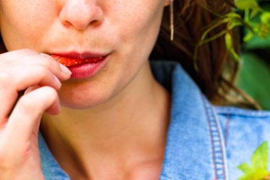 Kız çilek yumuşak ve taze bir parçası ısırır. Sulu berry ihale dudaklarını dokunur.