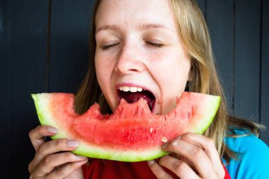 Bir güzel ve Genç kız sokması onun ağız taze, lezzetli ve sulu karpuz açın. O çok aç ve o yemek istiyor.