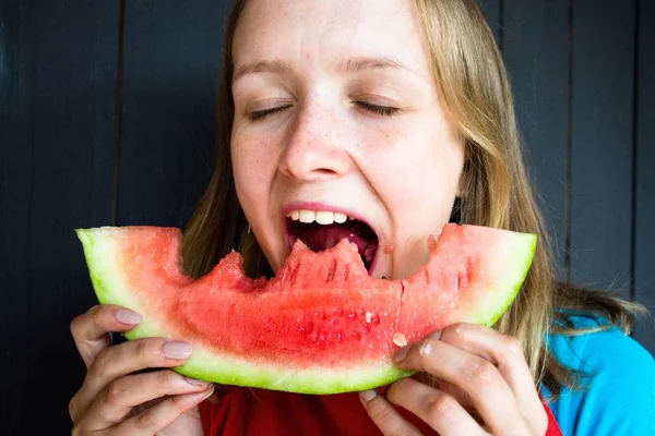 Bir güzel ve Genç kız sokması onun ağız taze, lezzetli ve sulu karpuz açın. O çok aç ve o yemek istiyor.