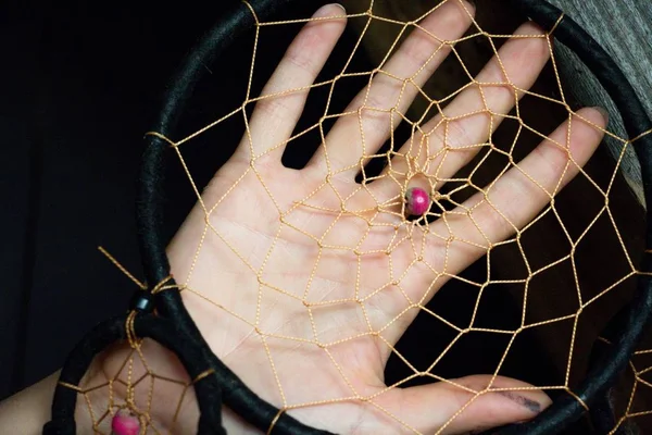 Detail of the catcher of dreams against the background of a gentle female hand. The detail of the dream catcher is like a spider web.
