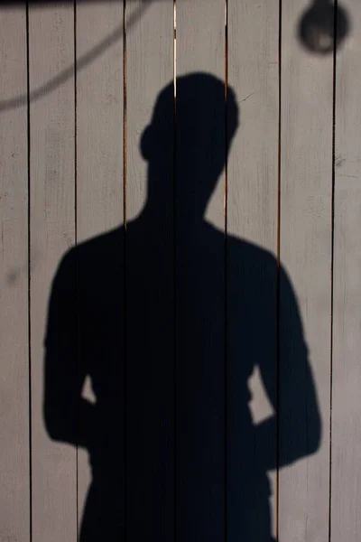 The shadow of a man falls on a black wooden surface. The surface is painted with paint. man stands out well against a dark background.