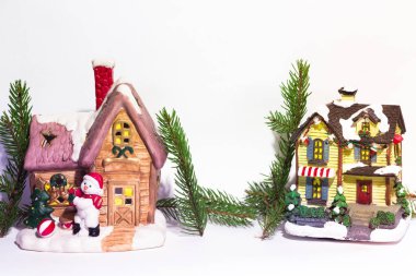 İki güzel bir şekilde dekore edilmiş yılbaşı evleri stand bir evin yanındaki beyaz bir arka plan üzerinde bir kardan adam olduğunu. Çam dalları evler. Harika bir Noel atmosfer.