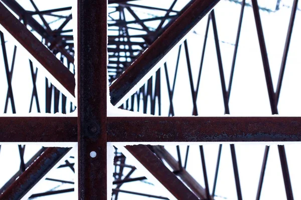 Abstract view of a huge pillar of metal conducting electricity. Its massive details are connected by large bolts.