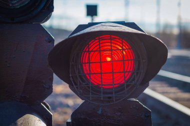 Tren hareketi uyarısı için demiryolunda bir trafik ışığı var. Trafik ışığı yaklaşan trenin kırmızı uyarısı ile yanıyor..