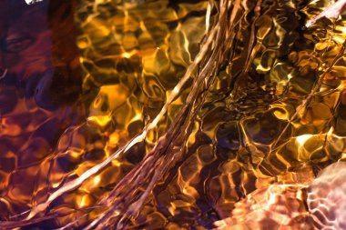 Parlak güneş ışınları akan suya yansır ve parlaklığına ihanet eder. Temiz bir liderde, taşlar ve algler en altta yükselir..