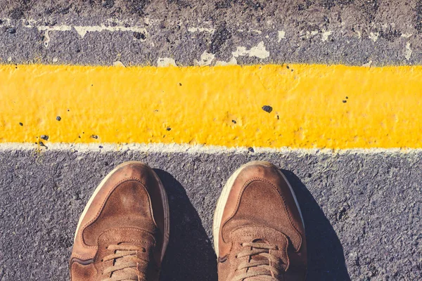一个人站在黄线旁边 鞋垫在人行道上灰色阴影 图库图片