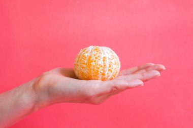 Soyulmuş mandalina nazik bir kadın elinde yatıyor. Portakal narenciye lezzetli ve sağlıklı bir meyve.