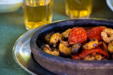 Domates ve biber ile lezzetli kızarmış karides. Karides ve sebze bitkisel yağ ve soya sosu ile bir sos kızartılmış. Çanak kil tabaklarda servis edilir.