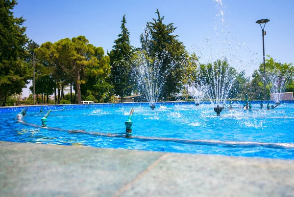 美丽的公园里有几个小喷泉 喷泉周围 树木生长 喷泉里的水很清澈 有蓝色的色调 图库图片