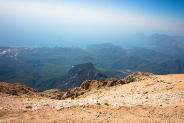 Dağın tepesinden güzel bir manzara. Çok dik kayalık iniş. Dağların, sedir ormanlarının, denizin ve şehrin panoramik manzarası.
