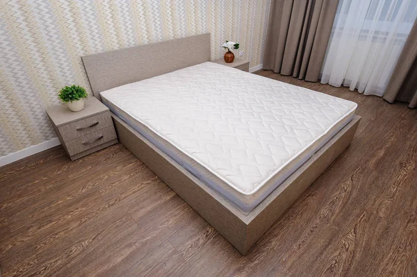 Новая пустая коричневая спальня с двуспальной кроватью, тумбочками и занавеской — стоковое фото