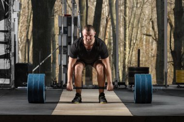 Deadlift girişimi. Ağır halter kaldırmak çalışan genç adam