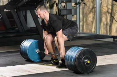 Deadlift girişimi. Ağır halter kaldırmak çalışan genç adam