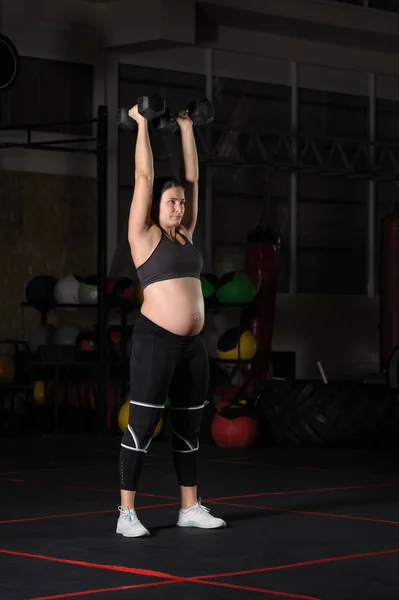 Pregnant female athlete doing dumbbell power snatch — Stock Photo, Image