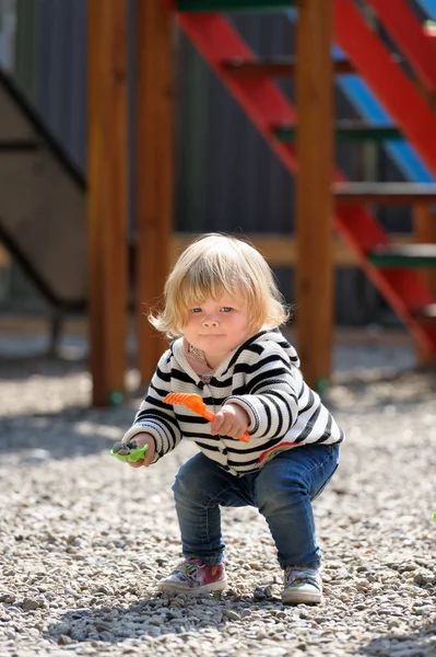 Linda niña jugando con la pala en el patio de recreo — Foto de Stock