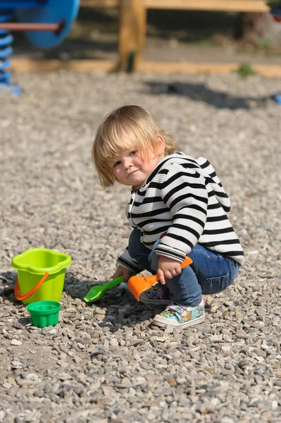 Linda niña jugando con la pala en el patio de recreo — Foto de Stock