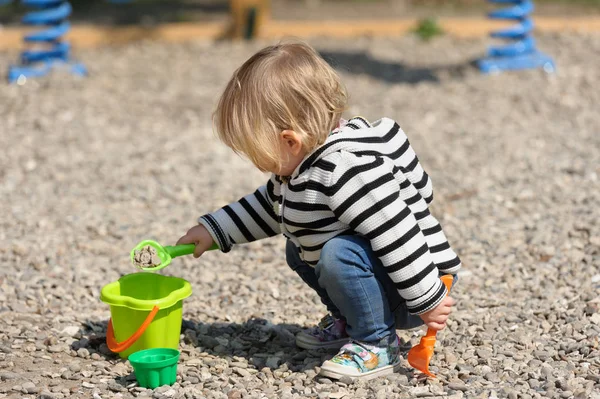 Cute toddler baby girl playing with shovel at playground — Stock Photo, Image