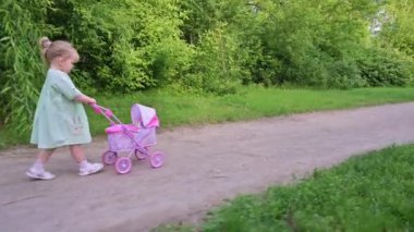 Küçük kız oyuncağıyla yaz parkında yürüyor.