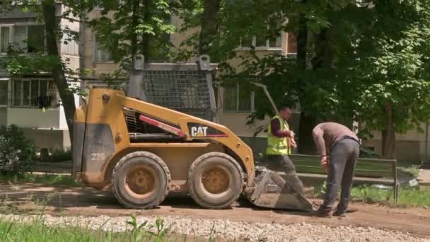 屋外の建設エリアで砂の土壌を移動するスキッドステアローダー — ストック動画