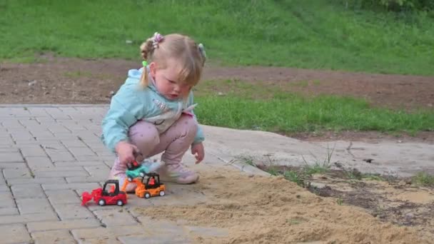 Liten flicka leker med leksaksbilar i sandlåda — Stockvideo