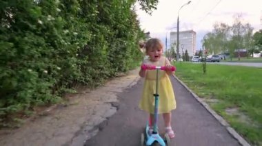 Küçük kız kaskı olmadan scooter kullanıyor.